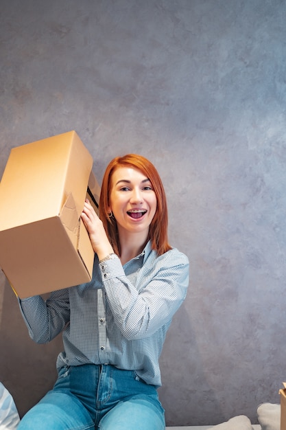 Young woman holding cardboard boxes and shakes it