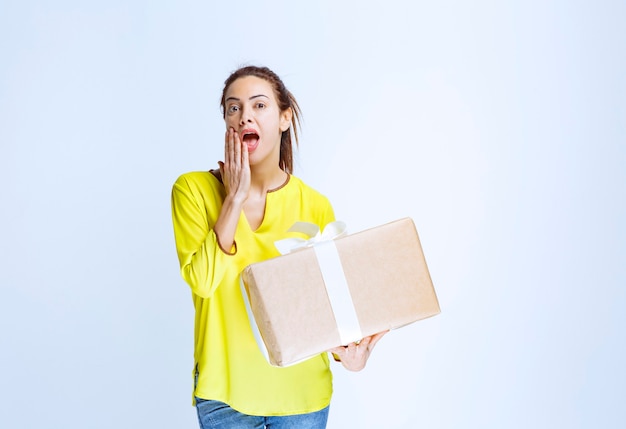 Young woman holding a cardboard gift box and thinking about the unknown sender