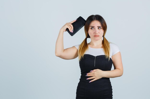 Young woman holding clutch over head