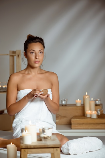 Free Photo young woman holding coconut, relaxing in spa salon.