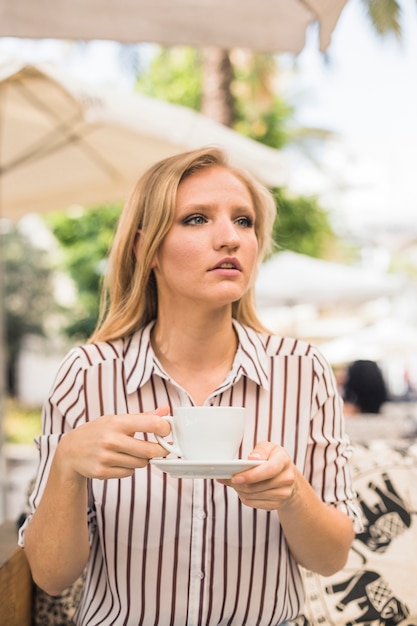 Young woman holding cup of coffee looking away