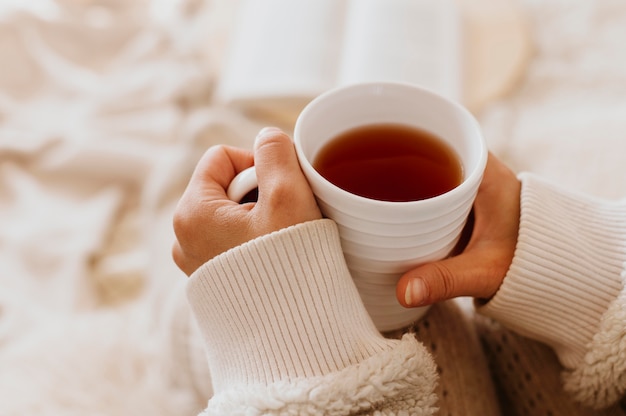 Free photo young woman holding a cup of tea while enjoying the winter holidays