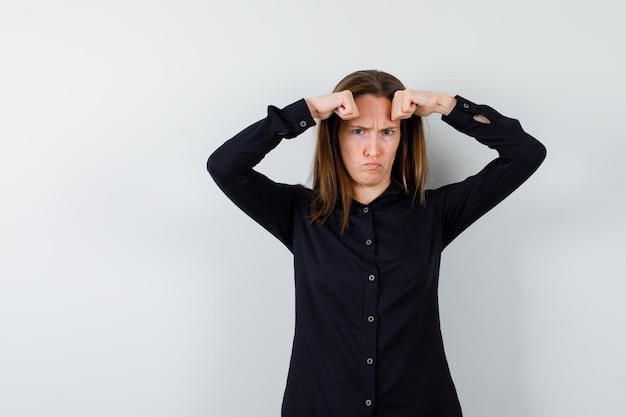 Free photo young woman holding fists on head and looking angry