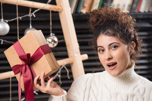 Free photo a young woman holding a gift box with bow