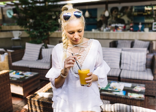 Free photo young woman holding glass of juice stirring with straw