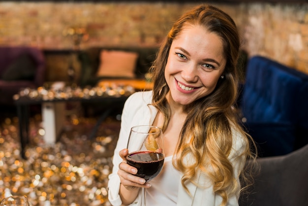 Free Photo young woman holding a glass of red wine in bar