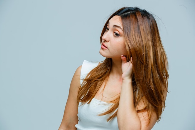 Young woman holding hand behind ear