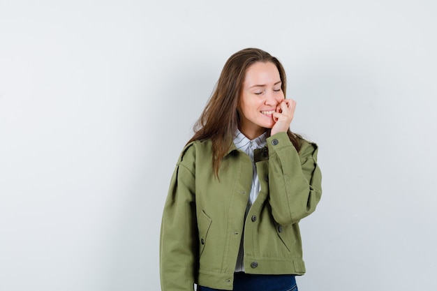 Free Photo young woman holding hand near mouth in shirt, jacket and looking peaceful. front view.