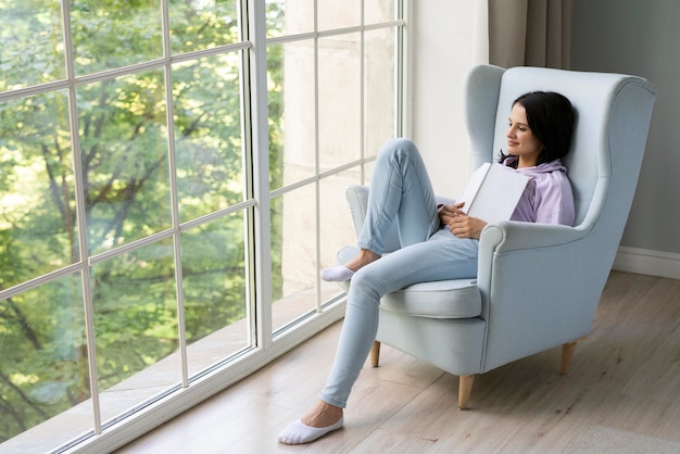 Young woman holding her book while looking out the window