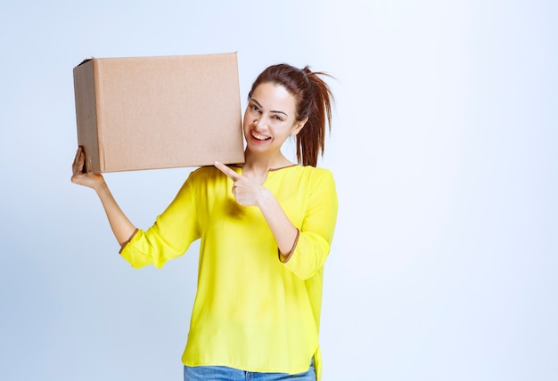 Young woman holding her cardboard parcel and introducing it