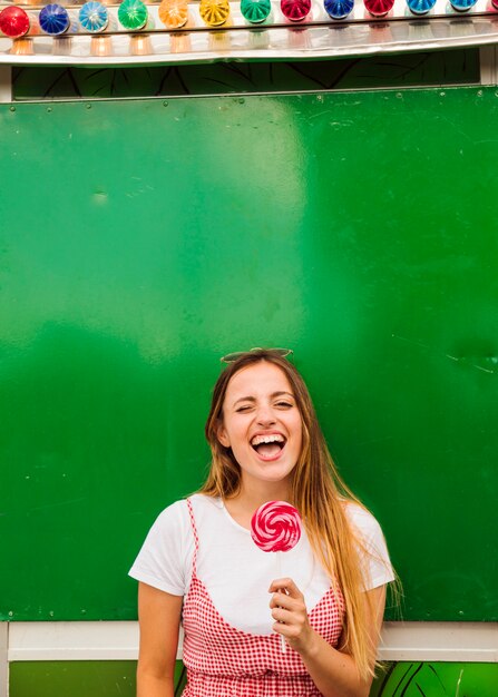 Young woman holding red lollipop in her hand laughing