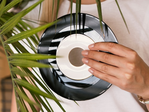 Free photo young woman holding retro vinyl record near plant