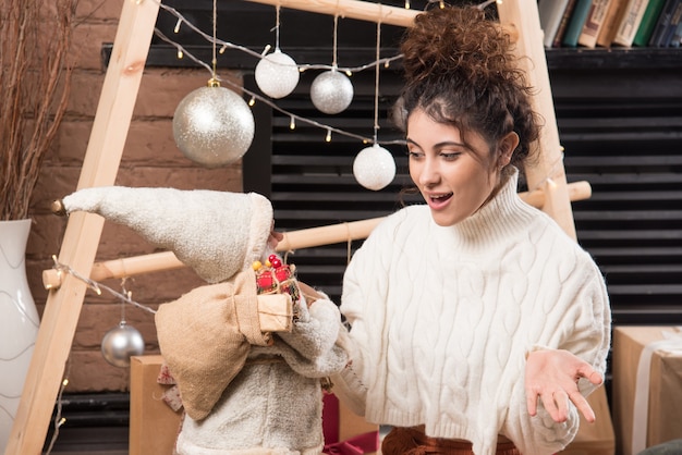 Free photo young woman holding a santa claus toy