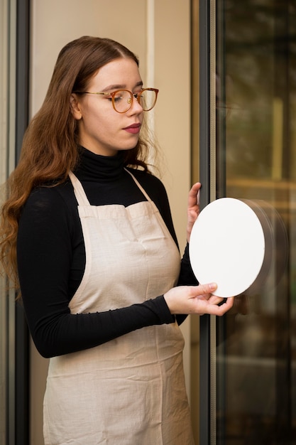 Young woman holding shop sign