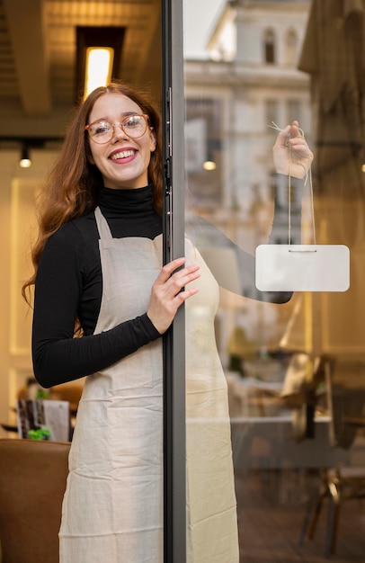 Free photo young woman holding shop sign