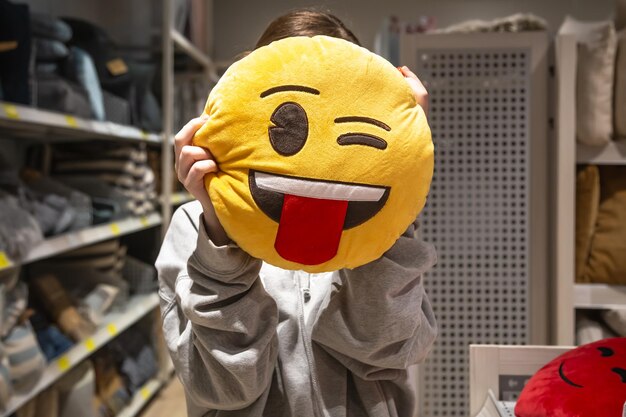 Young woman holding a smiley pillow in her hands in a store