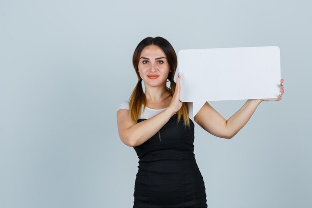 Young woman holding speech bubble and looking pleased