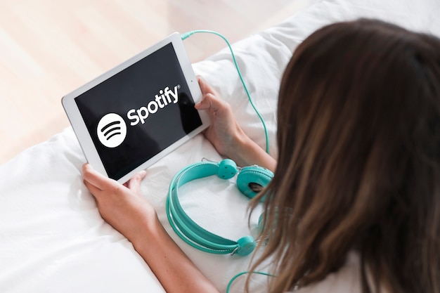 Young woman holding tablet with spotify app