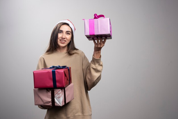 Young woman holding three boxes of Christmas presents.