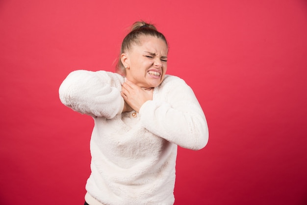 A young woman holding throat and suffering from pain