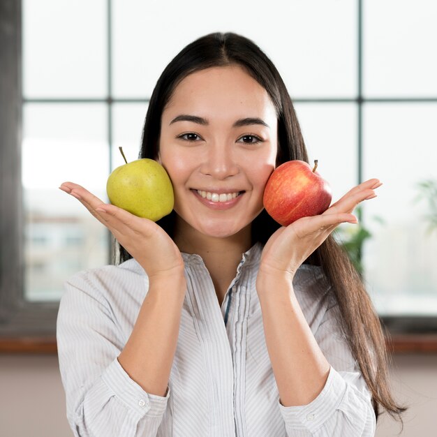 Young woman holding two green and red apple