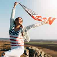 Free photo young woman holding waving flag of america