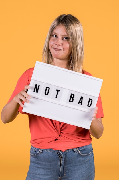 Young woman holding white light box with not bad text