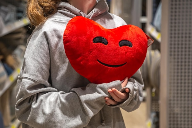 Free photo a young woman holds a heartshaped pillow in her hands in a store