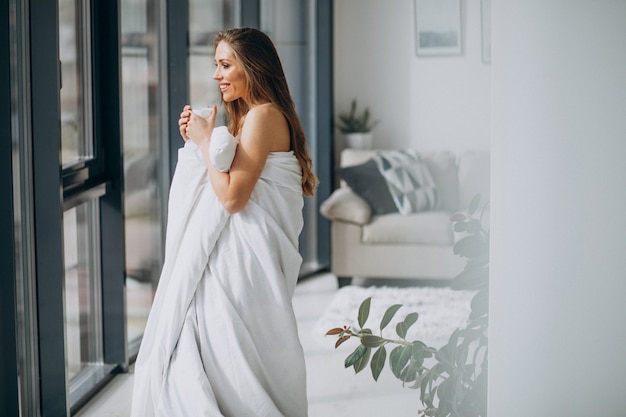 Young woman at home covered in blanket