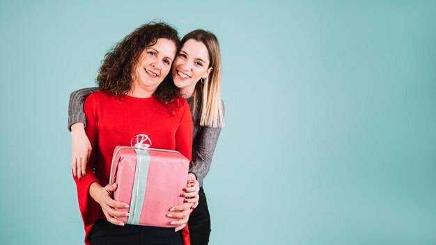 Young woman hugging mother with gift