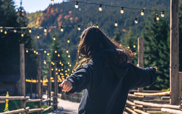 A young woman is dancing against the backdrop of mountains