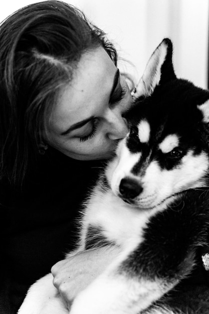 Free Photo a young woman is playing with a husky puppy