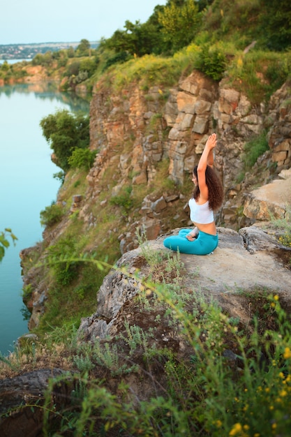 Free photo young woman is practicing yoga near river