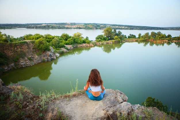 Free photo young woman is practicing yoga near river