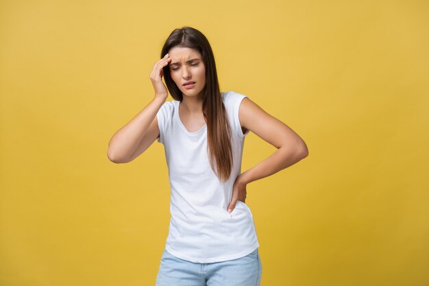 Young woman is suffering from a headache against a yellow background Studio shot