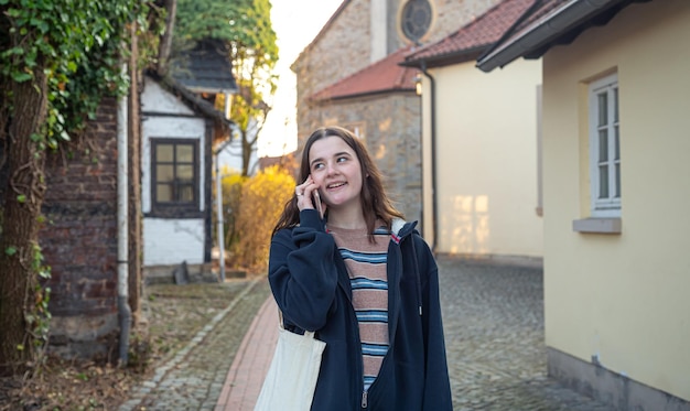 A young woman is talking on the phone on a walk in the town