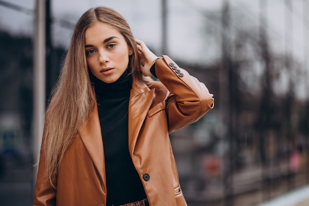 Young woman in jacket walking out in the city