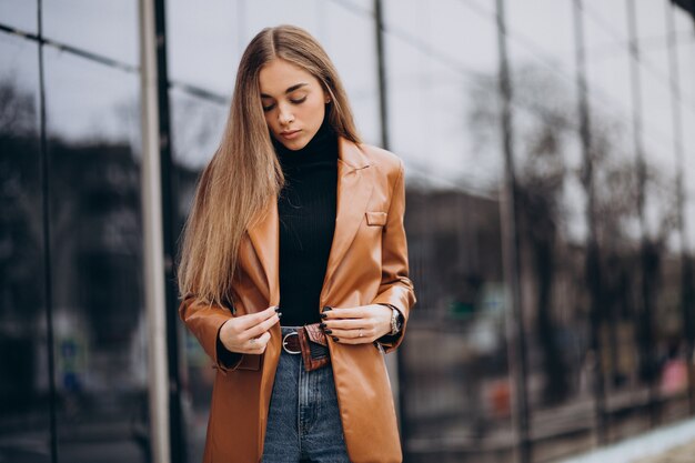 Young woman in jacket walking out in the city