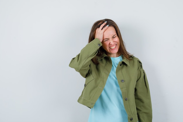 Free photo young woman keeping hand on head in t-shirt, jacket and looking annoyed. front view.