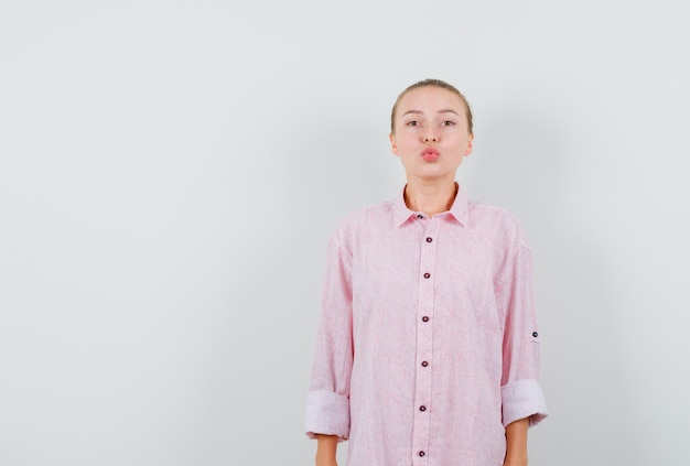 Free photo young woman keeping lips folded in pink shirt and looking pretty