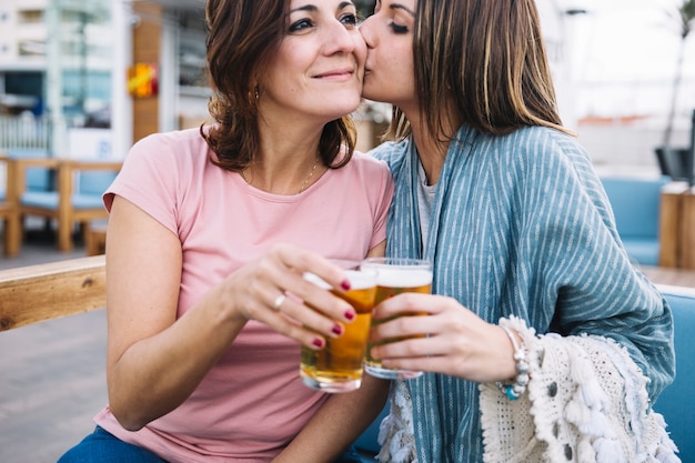 Young woman kissing woman while clinging glasses