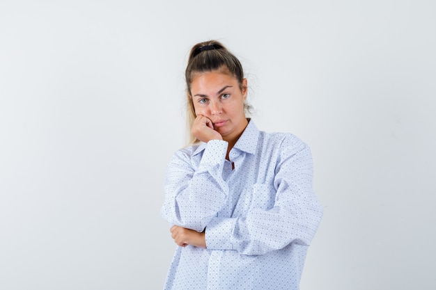 Young woman leaning cheek on palm while posing in white shirt and looking cute