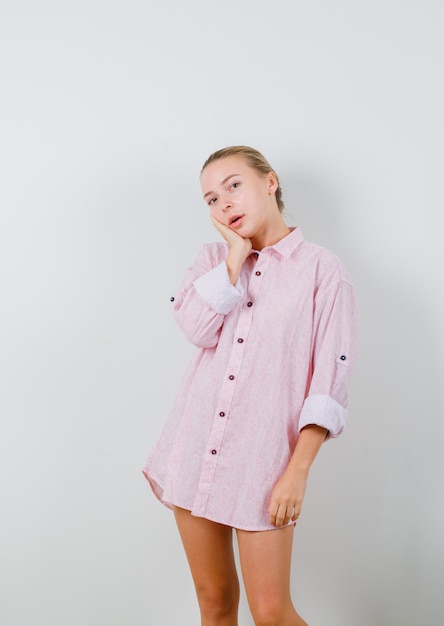 Free photo young woman leaning cheek on raised palm in pink shirt