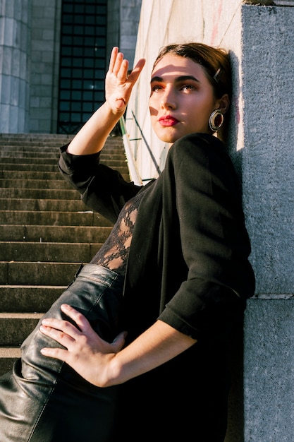 Free photo young woman leaning on wall shielding her eyes with hand from sunlight