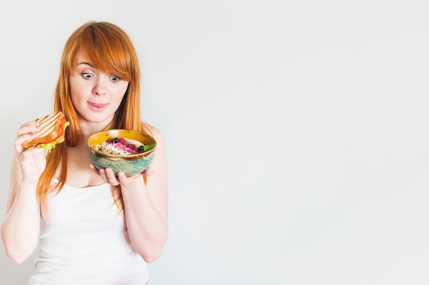 Young woman licking her tongue while looking at oatmeal bowl