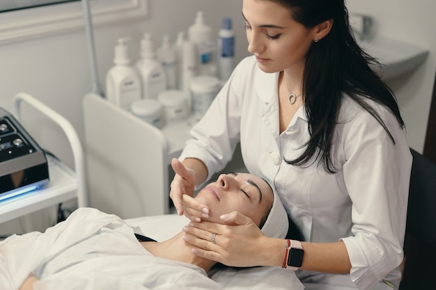 Free photo young woman lies with closed eyes, cosmetologist making procedure