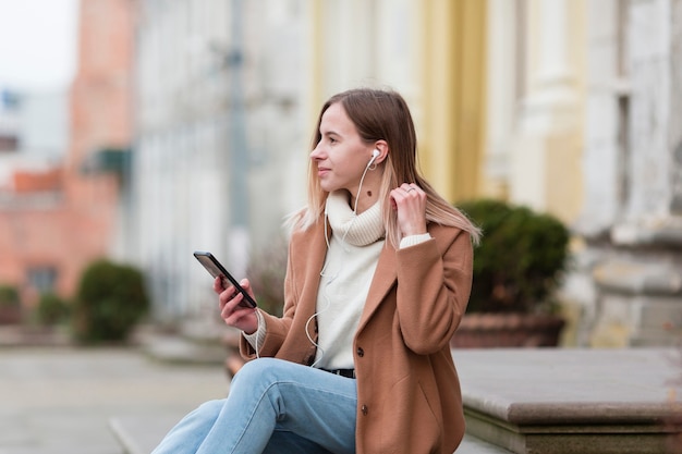 Young woman listening the music on earphones in the city