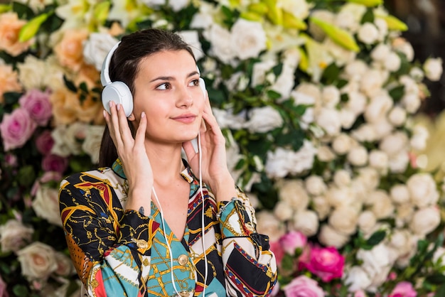 Free photo young woman listening to music in green house