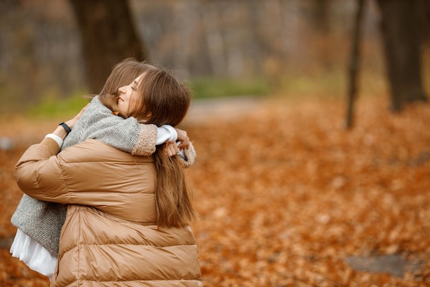 Free photo young woman and little girl in autumn forest woman and her daughter hugging girl wearing fashion grey dress with a jacket