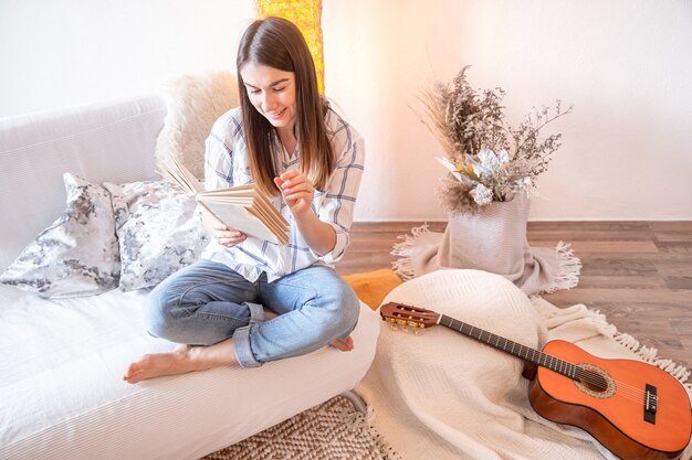 Young woman in the living room with a guitar.